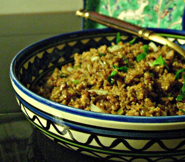 blue and white bowl filled with a cooked freekeh recipe and some green herbs cut on top.