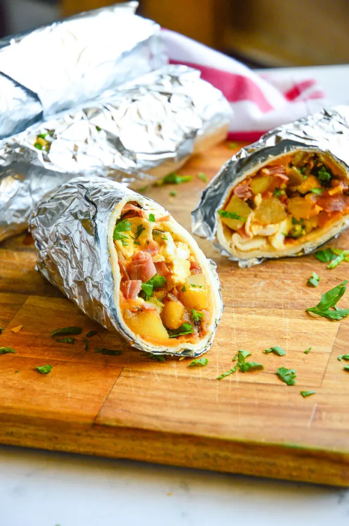 breakfast burrito in foil on cutting board