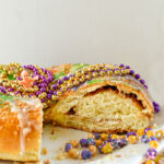 King Cake with cream cheese filling with colored sugar and mardi gras beads