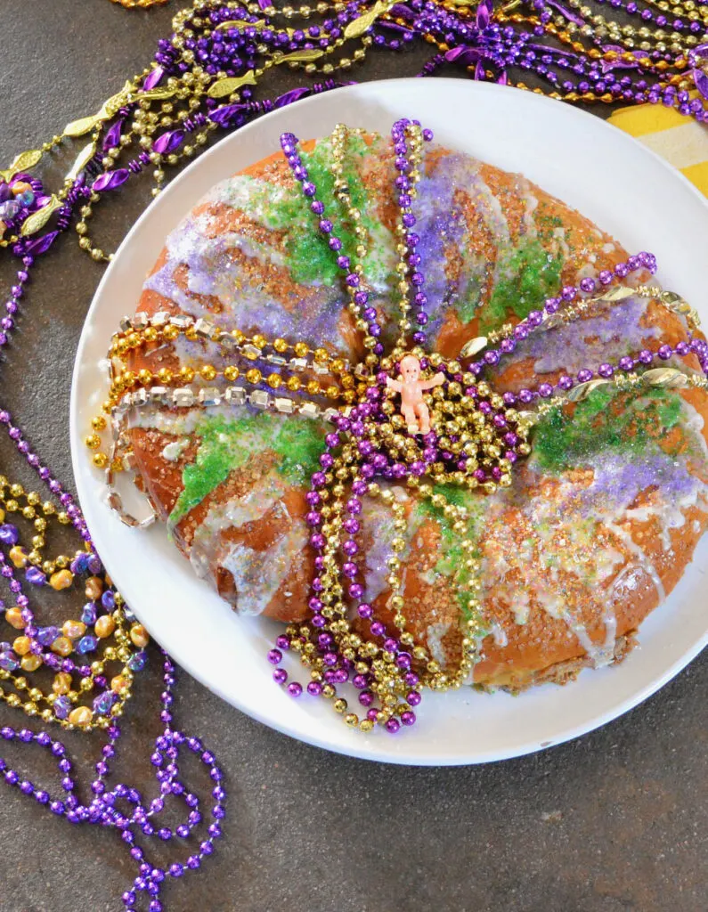 king cake with cream cheese filling and mardi gras beads with baby