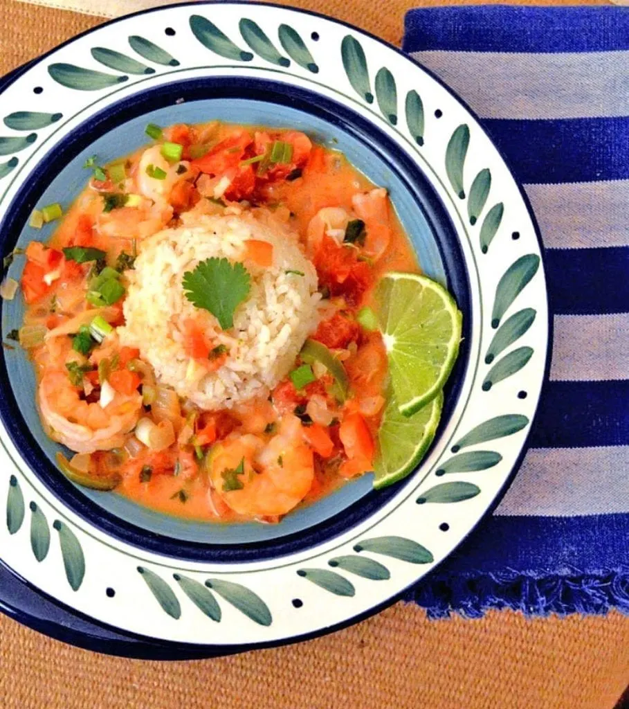 Brazilian Shrimp Stew with coconut and Lime in a white bowl with green dashes and a blue striped napkin