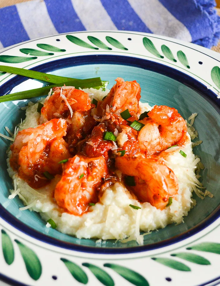 Shrimp and grits with tomatoes and cheese in white and green bowl