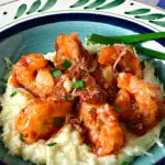 Creamy shrimp and Grits in green and blue bowl with blue napkin