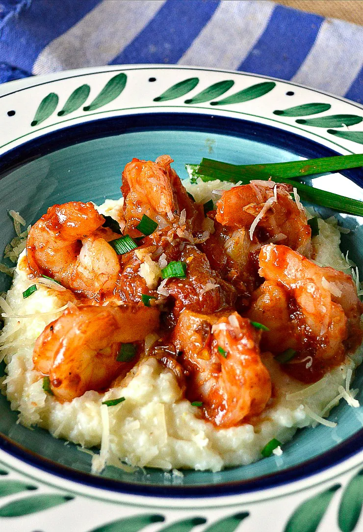 Creamy shrimp and Grits in green and blue bowl with blue napkin