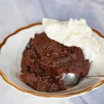 chocolate lava cake on gold rimmed saucer with whipped cream and spoon