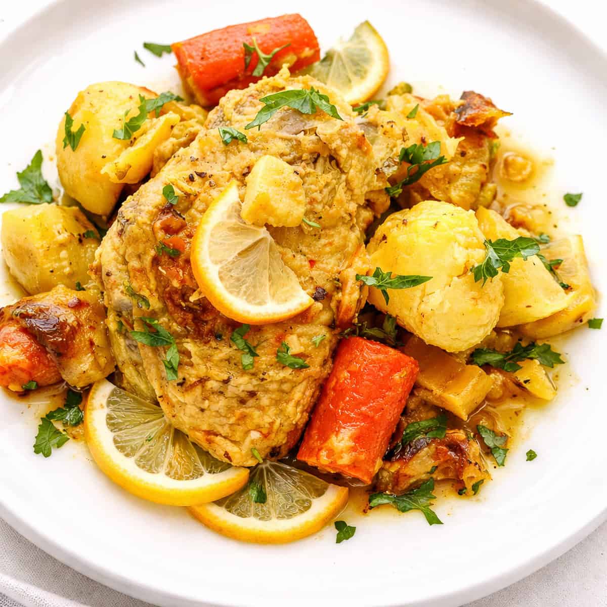 saffron chicken with potatoes and carrots on white plate