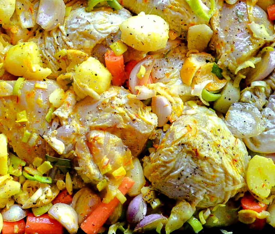 saffron chicken with carrots and leeks in pan before baking
