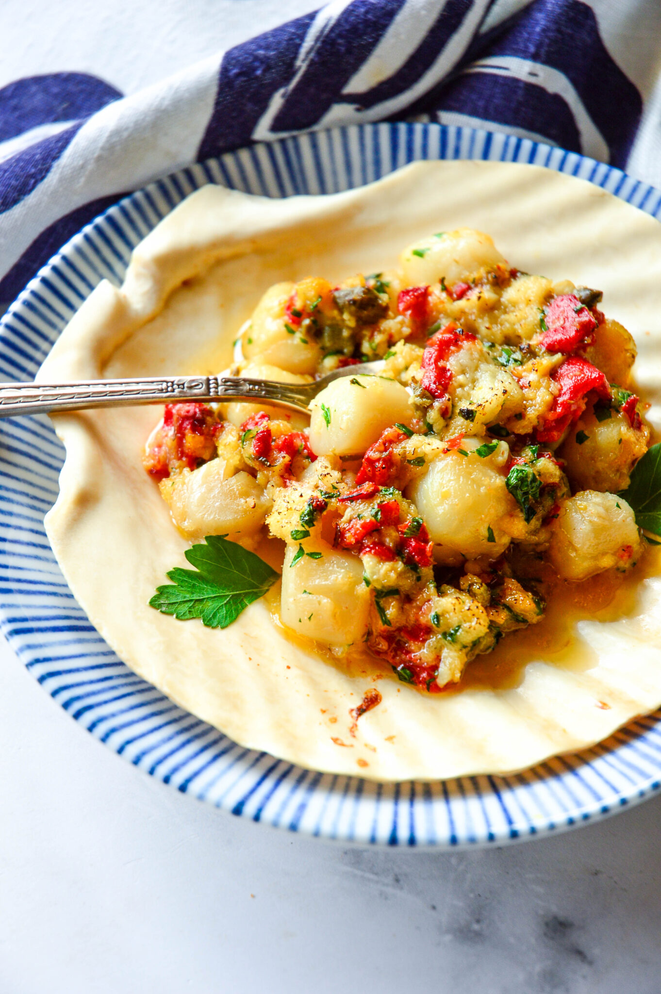 Pretty Bay Scallop Recipe in scallop shell on blue striped plate
