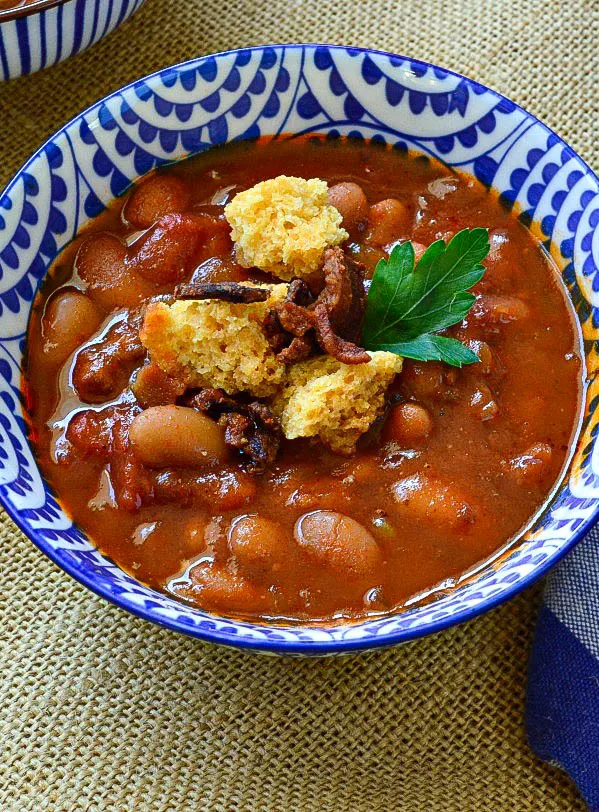 bean soup with sausage and cornbread croutons in blue and white bowl