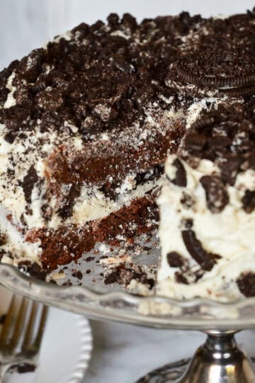 oreo cake on silver cake stand with slice out of it
