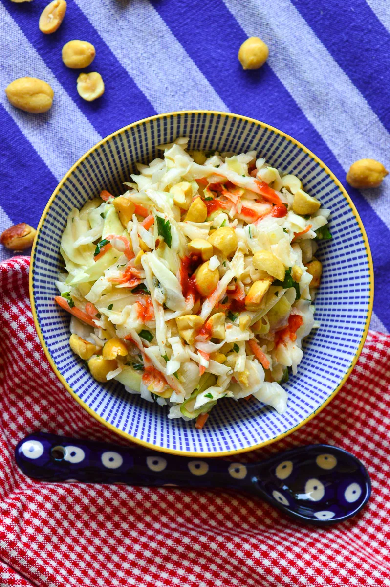 Coleslaw in blue and white bowl with blue polka dit spoon on red napkin