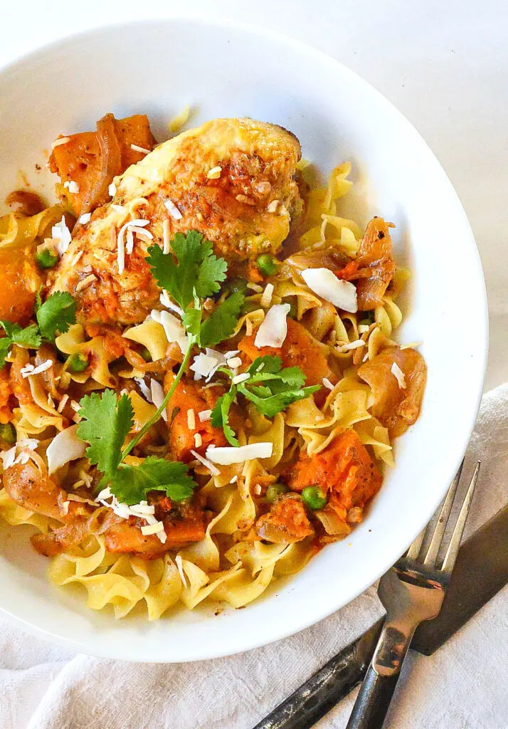 aji chicken and coconut in white bowl with noodles/spoon and fork