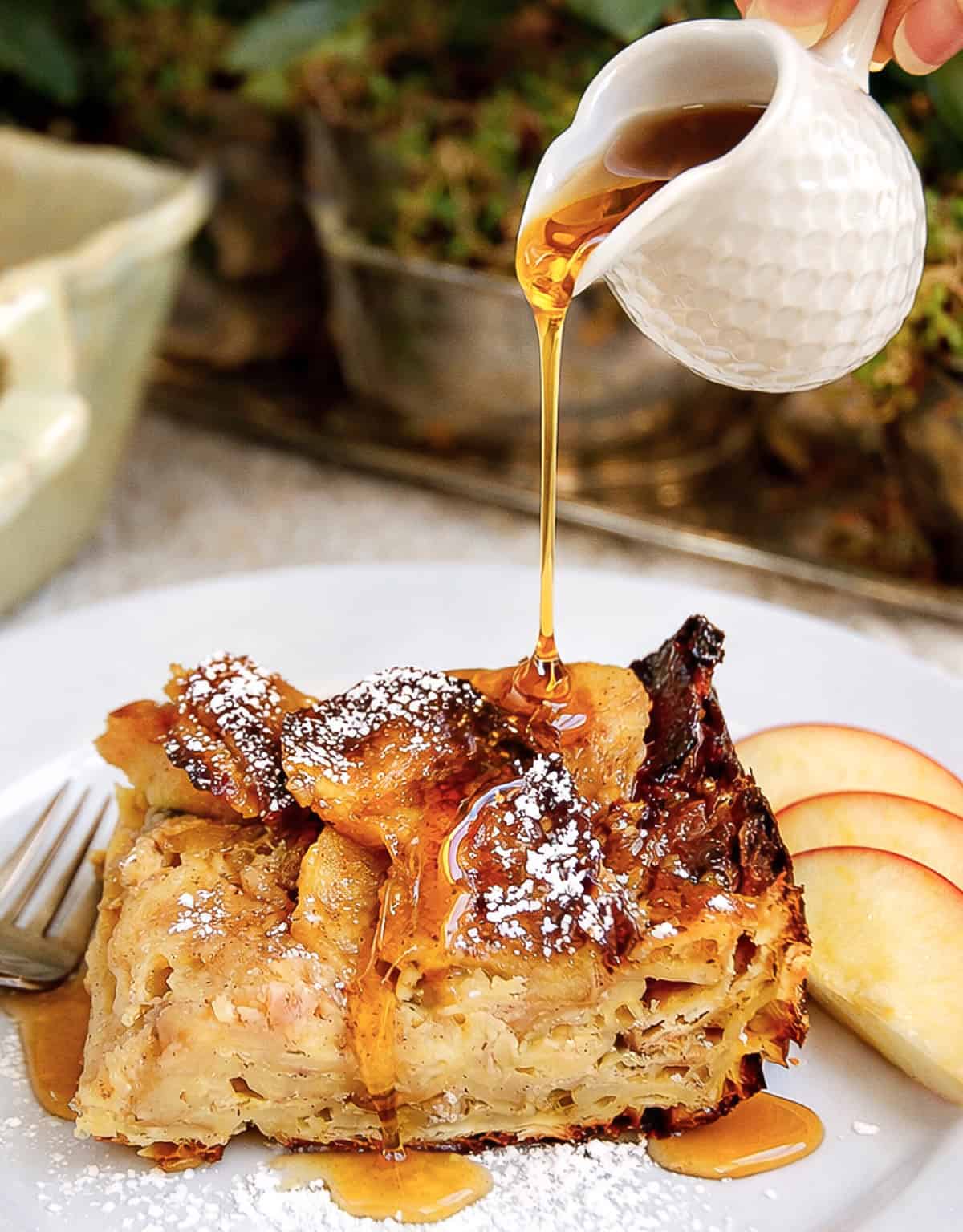 square of sweet matzo brei recipe with slices of apples and syrup drizzled on top