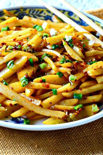 sichuan stir fried potatoes in chinese plate with chopsticks