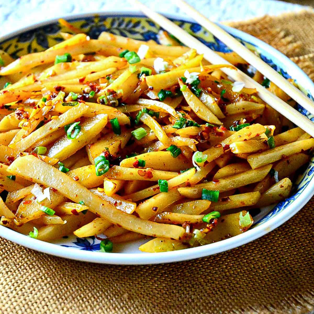 sichuan stir fried potatoes in chinese dish with chopsticks