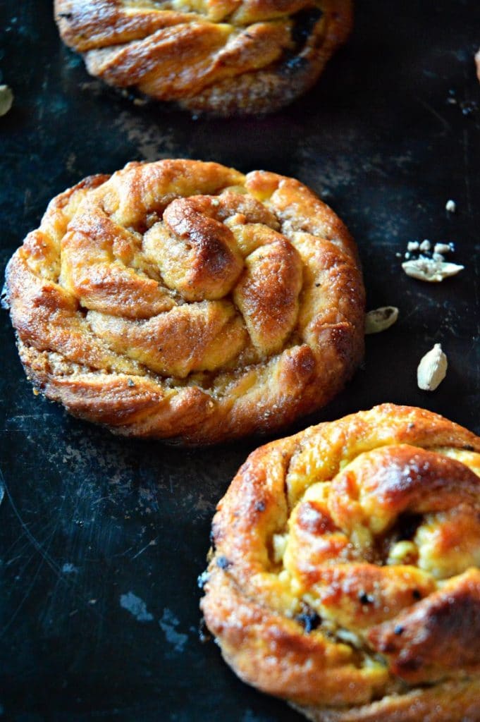 cardamom buns on black baking sheet