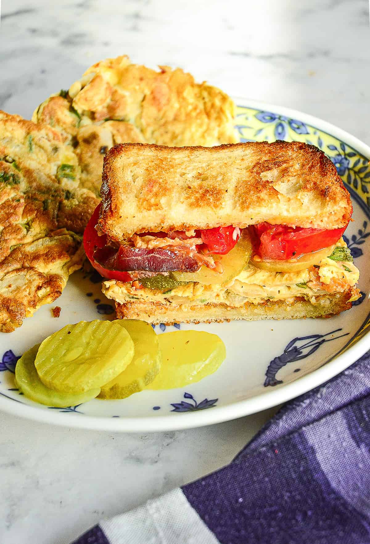 half of a st paul sandwich on plate with egg foo young patties in back