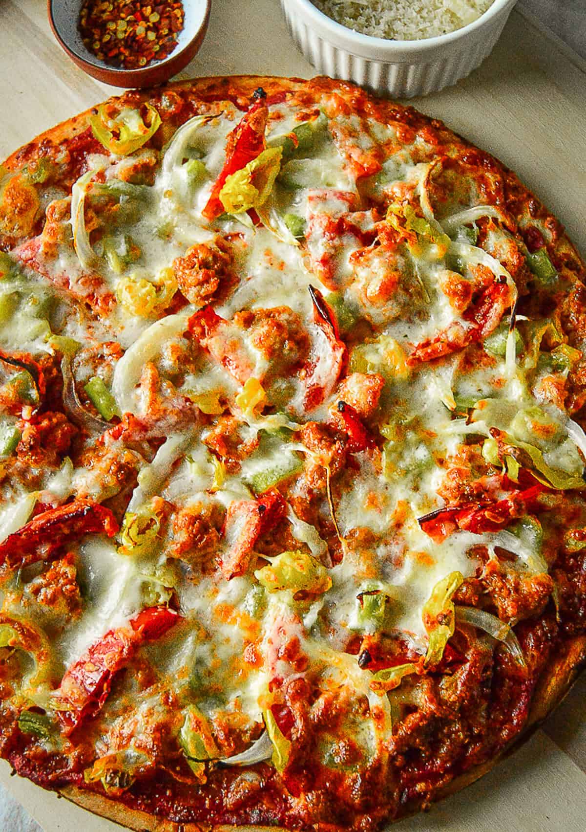 whole boboli pizza on pizza peel with cheese and pepper flakes