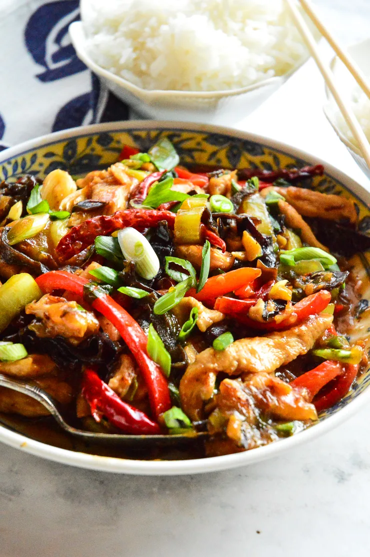 small bowls of white rice with big bowl of chinese chicken in garlic sauce with colored peppers and green onions.