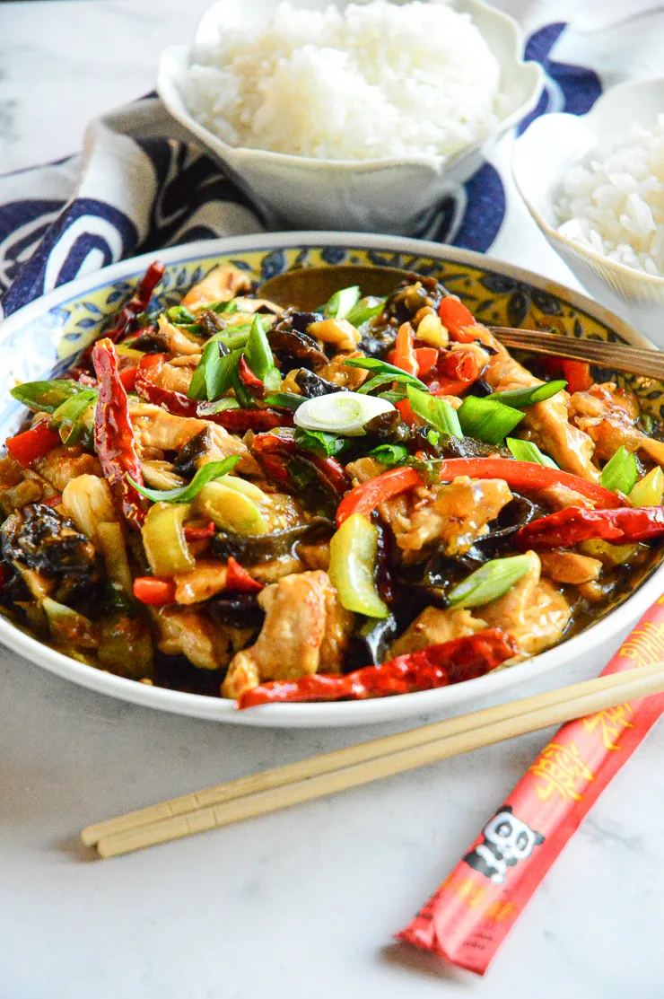 small bowls of white rice with big bowl of chinese chicken in garlic sauce with colored peppers and green onions.