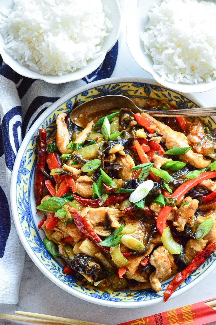 small bowls of white rice with big bowl of chinese chicken in garlic sauce with colored peppers and green onions.