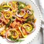 Lemon Butter Salmon in white plate with lemons, brown butter, dill and red onions