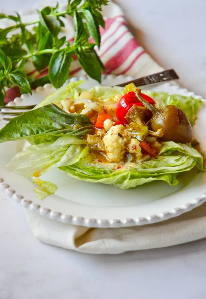 Iceberg Lettuce Salad with red peppers on red towel with fresh basil