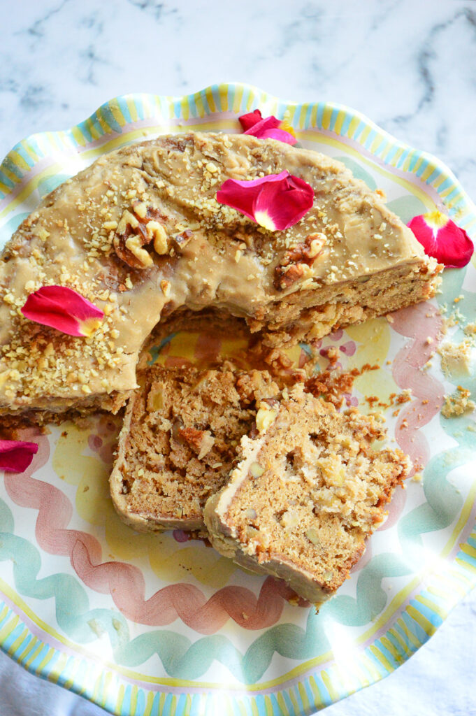 Jewish Apple cake with 2 slices and cake garnished with rose petals on platter