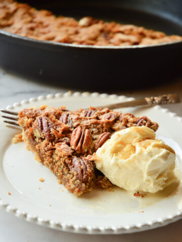 pecan pie slice with ice cream and whole pie behind