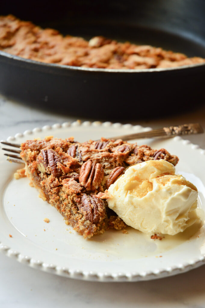 pecan pie slice with ice cream and whole pie behind