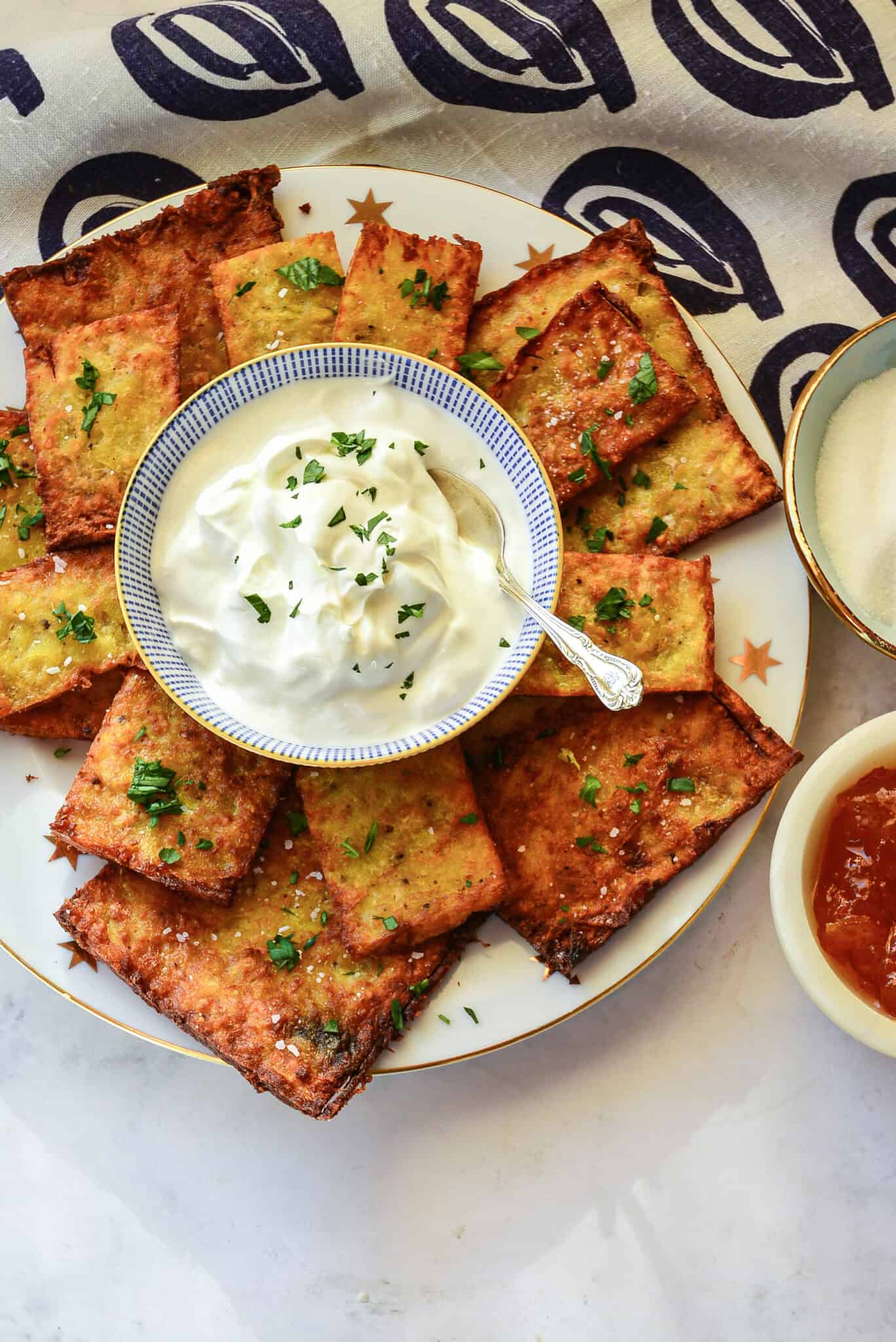 sheet pan latkes on platter with sour cream, blue napkin,