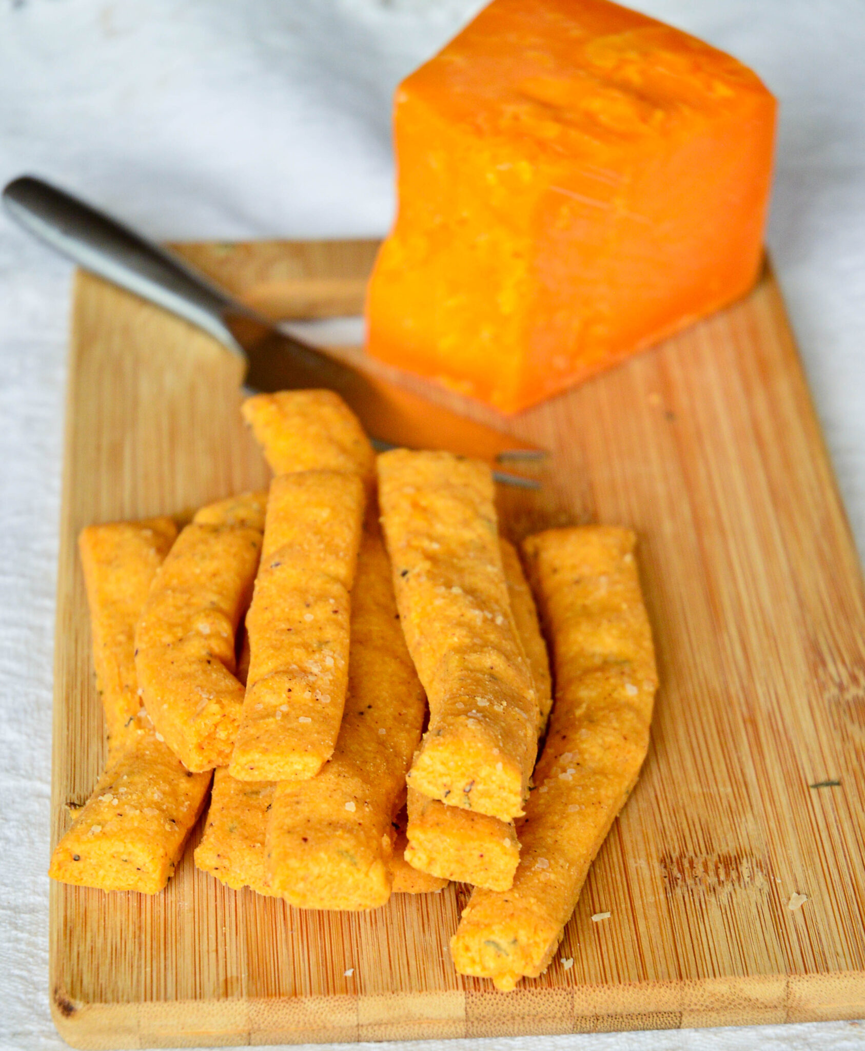 cheese straws cheese knife, wood board/wedge of cheddar