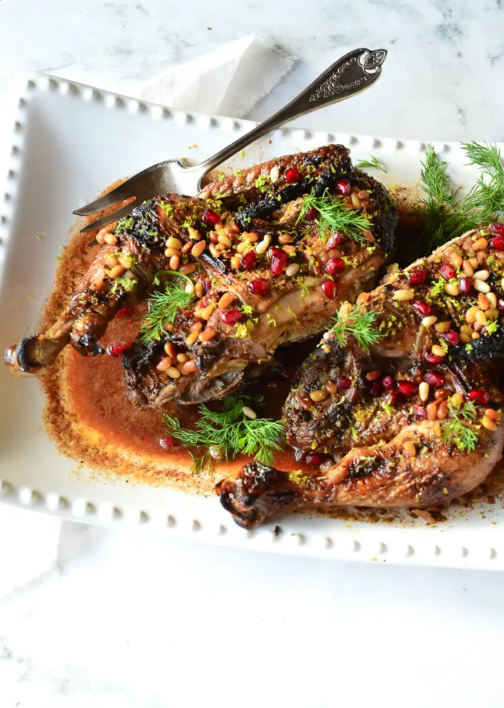 pomegranate chicke nrecipe in white platter with silver fork