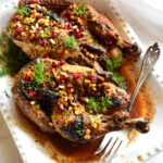 pomegranate chicken recipe on white platter with silver fork