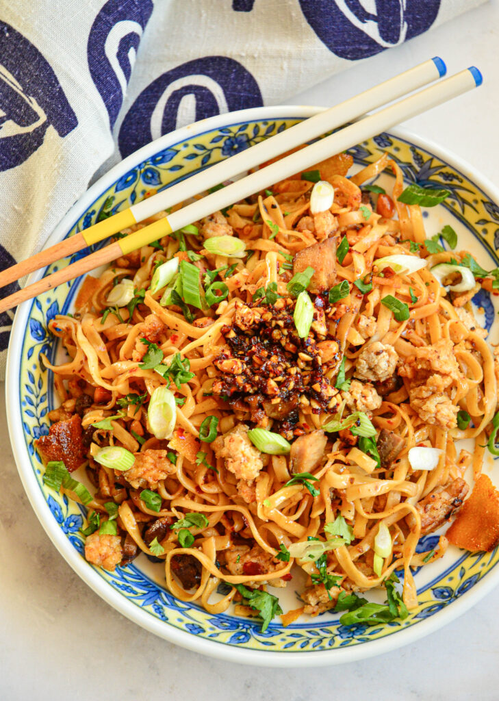 chili garlic noodles in asian blue bowl with chopsticks