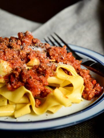 Giada's Bolognese Sauce on tagliatelle on blue banded plate with fork