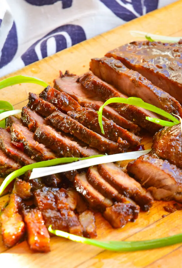 char siu barbeque pork recipe with scallions on cutting board