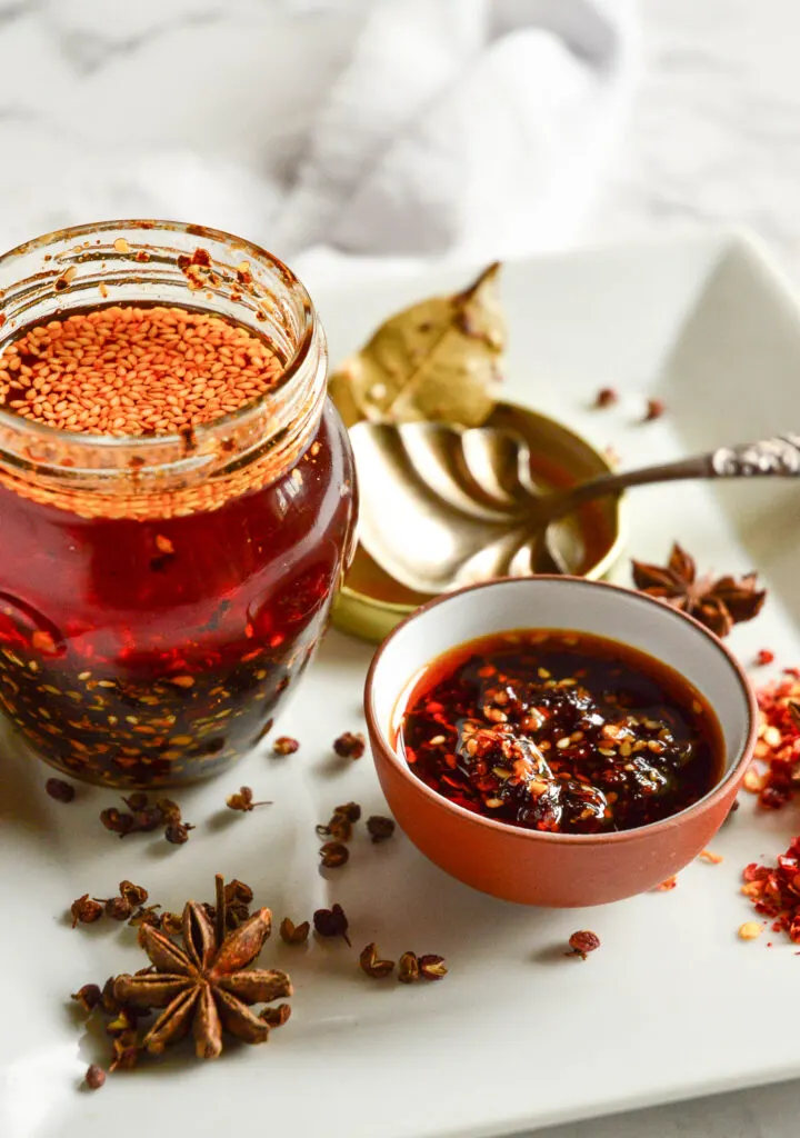 Chinese chili garlic sauce with spices and spoon on white plate
