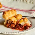 cherry pie with frozen cherries on white plate