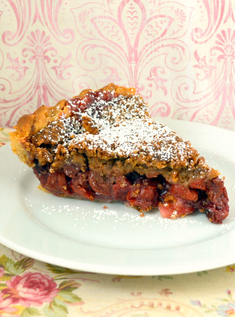 cherry pie with streusel topping on white plate