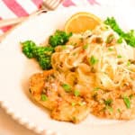 chicken piccata on white plate with broccolini and pasta