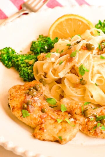 chicken piccata on white plate with broccolini and pasta