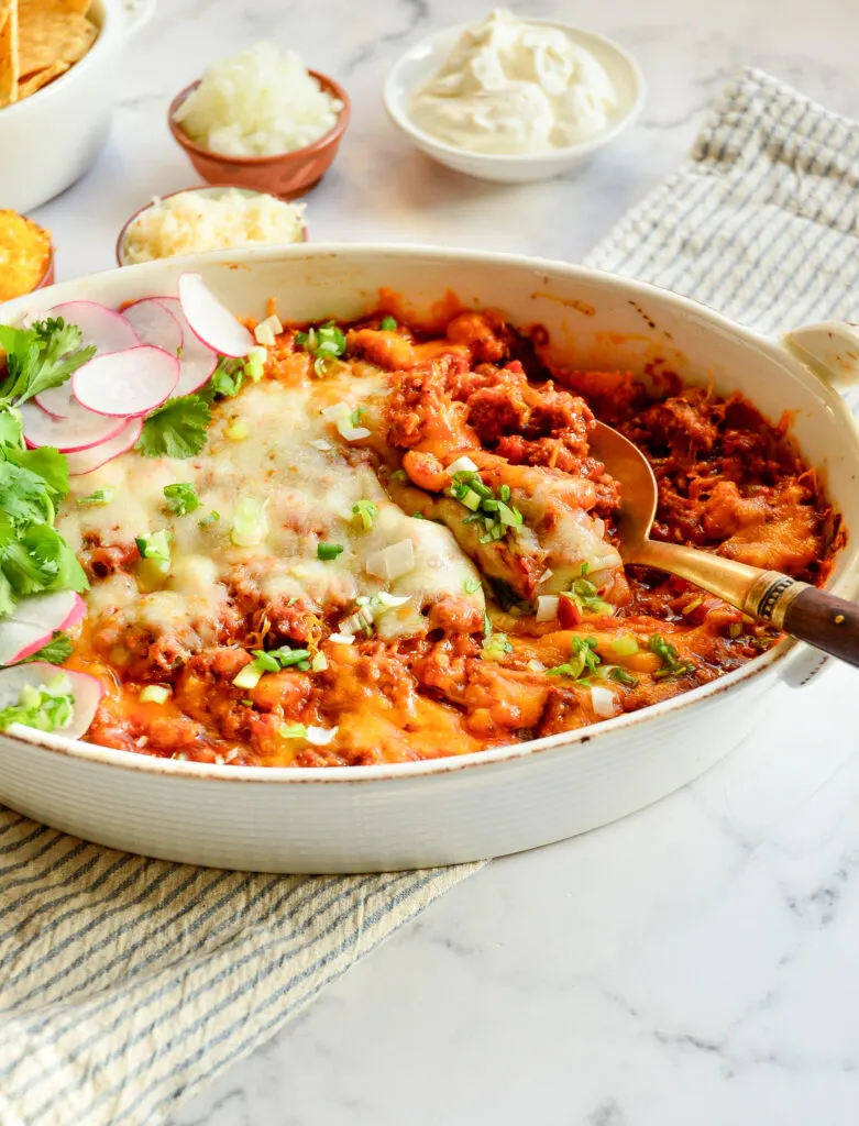 chicken taco casserole with serving spoon and toppings