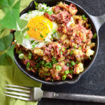corned beef hash breakfast recipe in cast iron skillet with green napkin