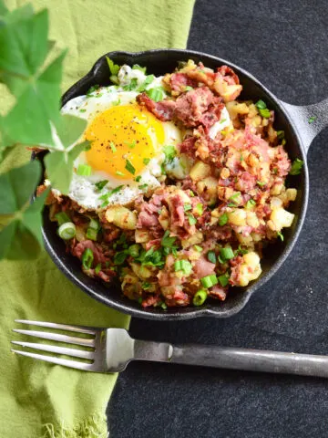 corned beef hash breakfast recipe in cast iron skillet with green napkin