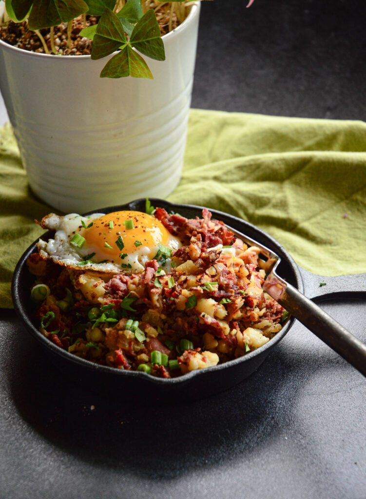 easy corned beef hash breakfast recipe in cast iron skiller with fork and green napkin