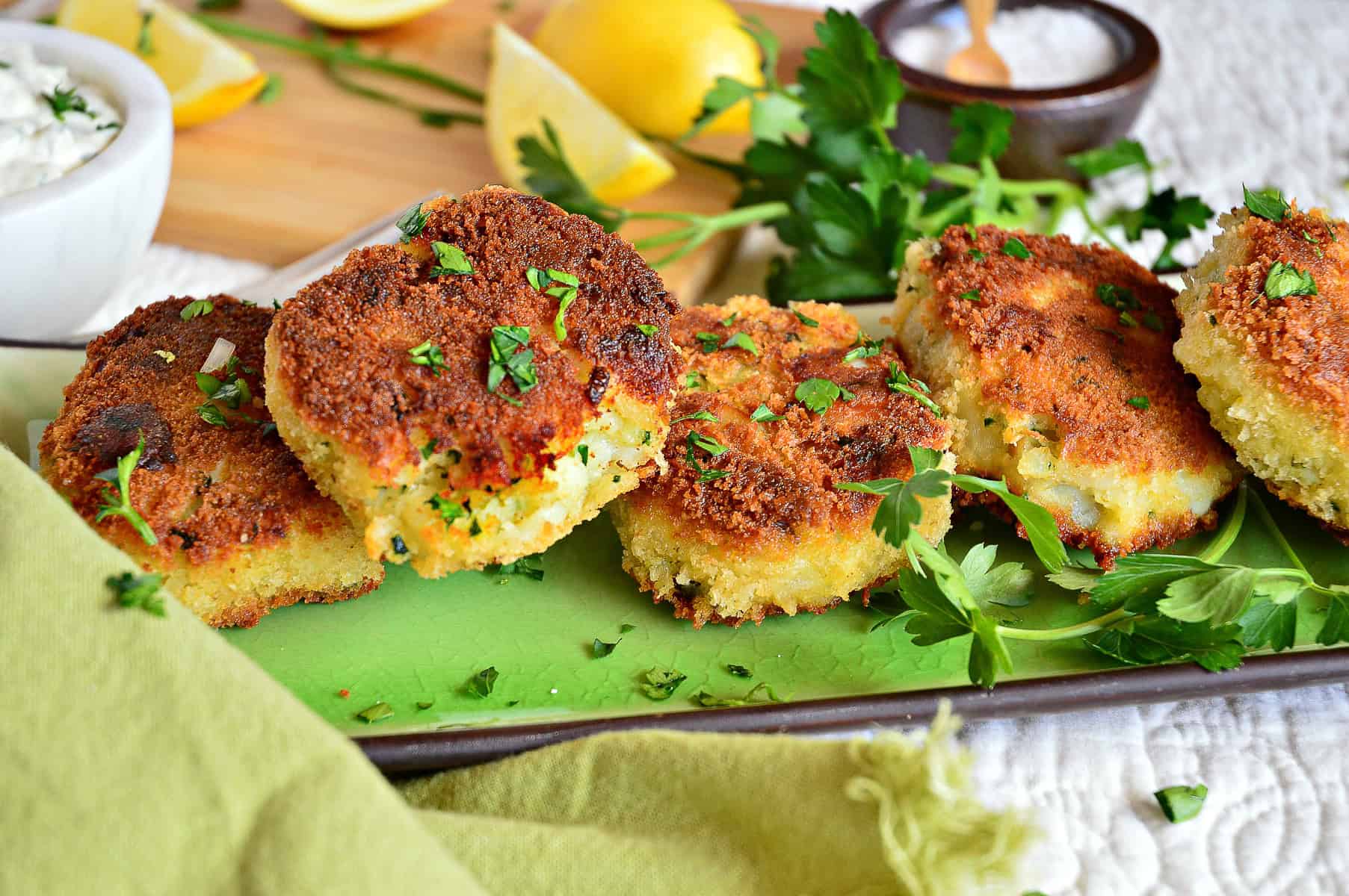 irish fish cod cakes on green rectangle tray with lemons and tartar sauce in background