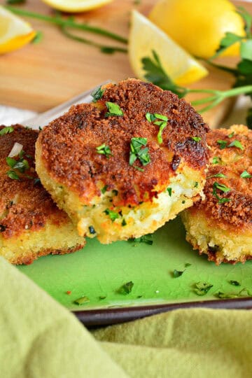 golden crisp irish cod fish cakes on green platter with lemons and parsley
