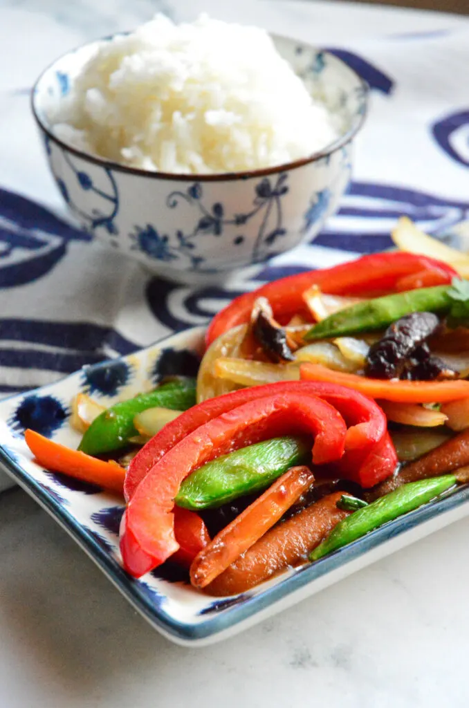 Chinese Vegetable Stir Fry Recipe on rectangle plate with rice bowl