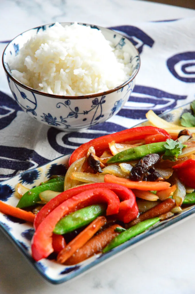 chinese stir fry vegetable recipe on blue platter with patterned blue rice bowl